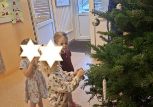 Zdjęcie przedstawia trzy dziewczynki z grupy I ubierające choinkę.