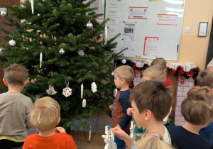 Zdjęcie przedstawia dzieci z grupy II ubierające choinkę.