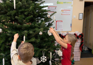 Na tym zdjęciu widać Natalkę z grupy II z kolegą wieszających ozdoby na choinkę.