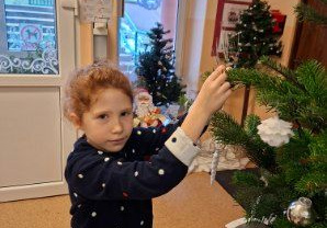 Zdjęcie przedstawia Mayę z grupy IV ubierającą choinkę.