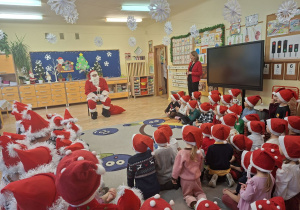 Na tym zdjęciu widać Mikołaja oraz dzieci siedzące na dywanie.