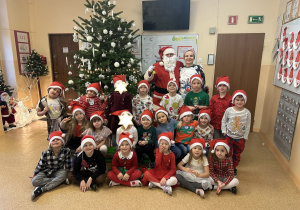 Zdjęcie przedstawia dzieci z grupy III wraz z panią i MIkołajem przy choince.