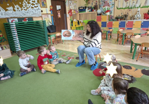 Na tym zdjęciu widać panią bibliotekarkę czytającą książkę oraz dzieci.