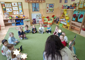 Zdjęcie przedstawia wszystkie dzieci słuchające bajki czytanej przez panią bibliotekarkę.