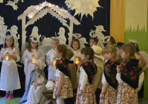 Zdjęcie przedstawia dziewczynki w roli góralek i aniołków z latarenkami oraz Alę R. w roli Maryi.