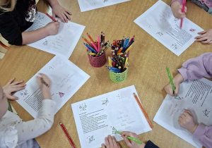 Zdjęcie przedstawia sześcioro dzieci z grupy I kolorujące elementy na dedykowanej kartce do pana Premiera.