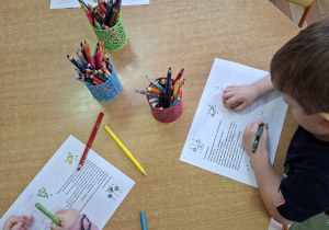 Zdjęcie przedstawia troje dzieci z grupy I kolorujące elementy na dedykowanej kartce do pana Premiera.