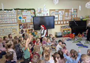 Zdjęcie przedstawia Oskara z grupy III śpiewającego kolędę oraz inne dzieci wraz z prowadzącym.