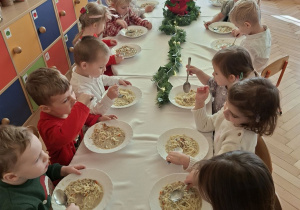Na tym zdjęciu widać dzieci spożywające wigilijną zupę przy wspólnym stole.