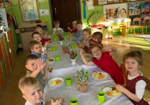 Zdjęcie przedstawia dzieci spożywające drugie danie z rybą przy wspólnym stole.