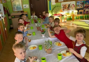 Zdjęcie przedstawia dzieci spożywające drugie danie z rybą przy wspólnym stole.