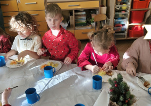 Na tym zdjęciu widać dzieci spożywające drugie danie z rybą przy wspólnym stole.