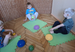 Zdjęcie przedstawian trzech chłopców wykonujących ćwiczenia stóp z przyborem.