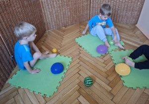 Zdjęcie przedstawian trzech chłopców wykonujących ćwiczenia stóp z przyborem.