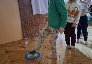 Na tym zdjęciu wdać dzieci z grupy II wykonujące ćwiczenia stóp z wykorzystaniem woreczka.