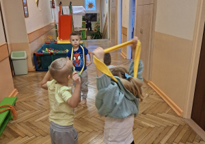 Zdjęcie przedstawia Natalkę i Damiana z grupy II wykonujących ćwiczenia z wykorzystaniem szarf.