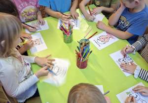 Zdjęcie przedstawia kilkoro dzieci z grupy IV kolorujące wybrane przez siebie obrazki, przedstawiające różne stany emocjonalne.
