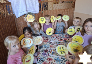 Zdjęcie przedstawia dzieci preznetujące gotowe emotikony wykonane przez siebie.