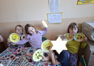 Zdjęcie przedstawia dzieci preznetujące gotowe emotikony wykonane przez siebie.