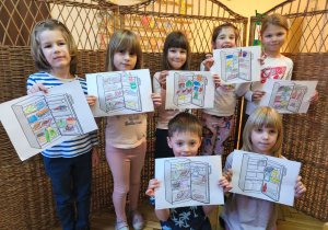 Na tym zdjęciu widać kilkoro dzieci z grupy IV prezentujące wykonane podczas zajęć teoretycznych prace plastyczne przedstawiające lodówkę z wyposażeniem.