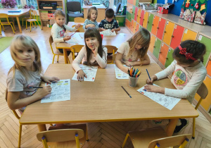 Zdjęcie przedstawia dzieci z grupy IV kolorujące i wycinające elementy wyposażenia lodówki.