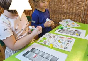 Zdjęcie przedstawia Mikołaja z koleżanką z grupy III wykonujących kartę pracy - lodówkę z wyposażeniem.