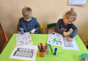 Zdjęcie przedstawia Oliwię i Adasia z grupy III wykonujących kartę pracy - lodówkę z wyposażeniem.