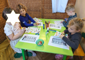 Zdjęcie przedstawia czworo dzieci z grupy III wykonujących kartę pracy - lodówkę z wyposażeniem.