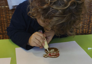 Na tym zdjęciu widać Mikołaja z grupy III ozdabiającego pierniczki.