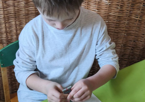 Na tym zdjęciu widać Stasia z grupy IV ozdabiającego lukrem wefelek ryżowy, tworząc bombkę.