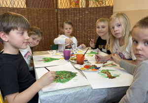 Zdjęcie przedstawia kilkoro dzieci malujących farbami.