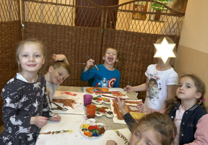 Zdjęcie przedstawia kilkoro dzieci malujących farbami