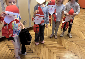 Na tym zdjęciu widać dzieci prezentujące wykonane przez siebie ozdoby na drzwi w formie Mikołaja.