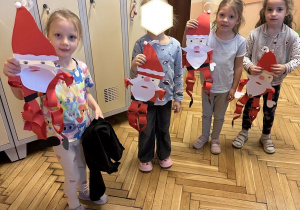 Na tym zdjęciu widać dzieci prezentujące wykonane przez siebie ozdoby na drzwi w formie Mikołaja.