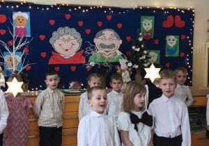 Zdjęcie przedstawia Tomka i Adasia wraz z koleżanką recytujących wierszyk.