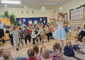Na tym zdjęcu widać chłopców ćwiczących elementy tańca baletowego pod okiem jednej z tancerek.