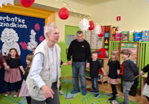 Zdjęcie przedstawia Seniorów oraz dzieci podczas wspólnej zabawy.