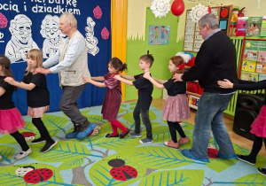 Zdjęcie przedstawia Seniorów oraz dzieci podczas wspólnej zabawy.