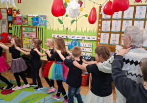 Zdjęcie przedstawia Seniorów oraz dzieci podczas wspólnej zabawy.