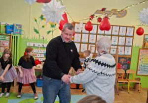 Zdjęcie przedstawia Seniorów oraz dzieci podczas wspólnej zabawy.