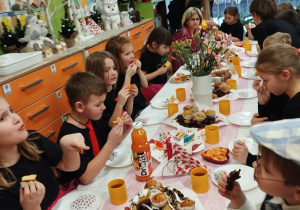 Na tym zdjęciu widać dzieci z grupy IV siedzące przy stole podczas poczęstunku.
