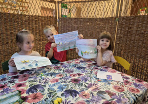 Na tym zdjęciu widać troje dzieci pokazujących gotowe prace.