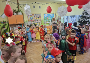 Zdjęcie przedstawia dzieci z grupy III oraz dzieci z grupy II podczas zabawy w korowodach.