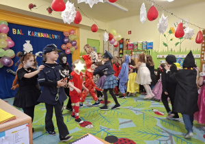 Na tym zdjęciu widać dzieci biorące udział w zabawach karnawałowych przy muzyce.