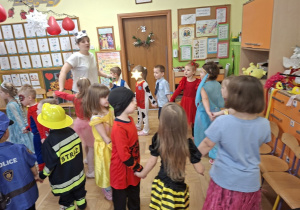 Zdjęcie przedstawia dzieci z grupy III wraz z nauczycielką podczas zabawy karnawałowej.