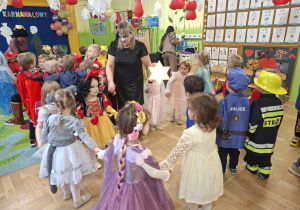 Zdjęcie przedstawia dzieci z grupy I wraz z nauczycielką podczas zabawy karnawałowej.