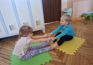 Zdjęcie przedstawia Lenę R. i Henia D. z grupy I wykonujących ćwiczenia wiloznaczne, ogólnorozwojowe w parach.