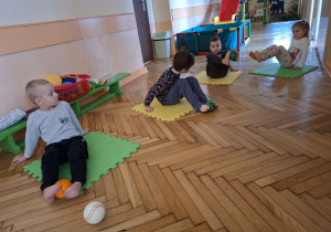 Na tym zdjęciu widać czworo dzieci z grupy II, uczestników projektu wykonujących ćwiczenia przeciw płaskostopiu z piłką.