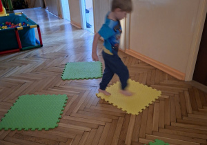 Zdjęcie przedstawia Damiana z grupy I podczas wykonywania ćwiczenia rozwijającego zachowanie równowagi ciała.