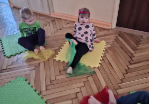 Na tym zdjęciu widać Henia D., Natalkę oraz Damiana z grupy I wykonujących ćwiczenia przeciw płaskostopiu z chustkami.